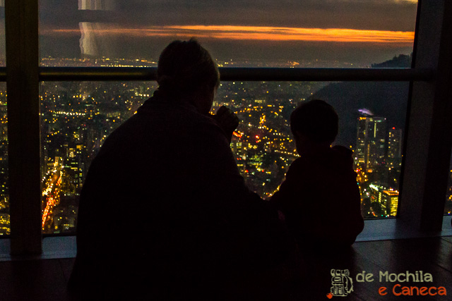 Pai e filho observam Santiago toda iluminada. Visual
